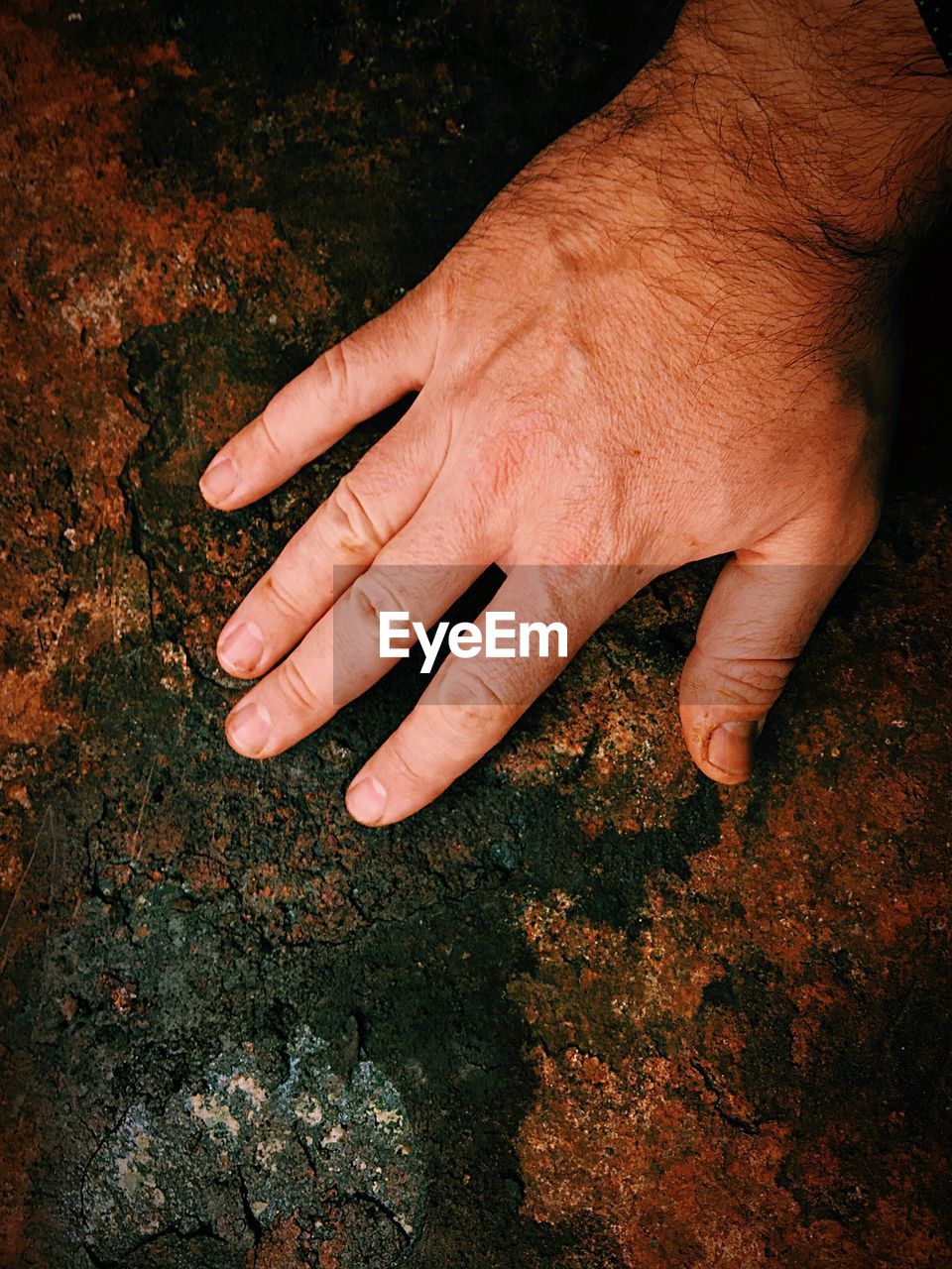 Cropped hand of man touching rusty metal