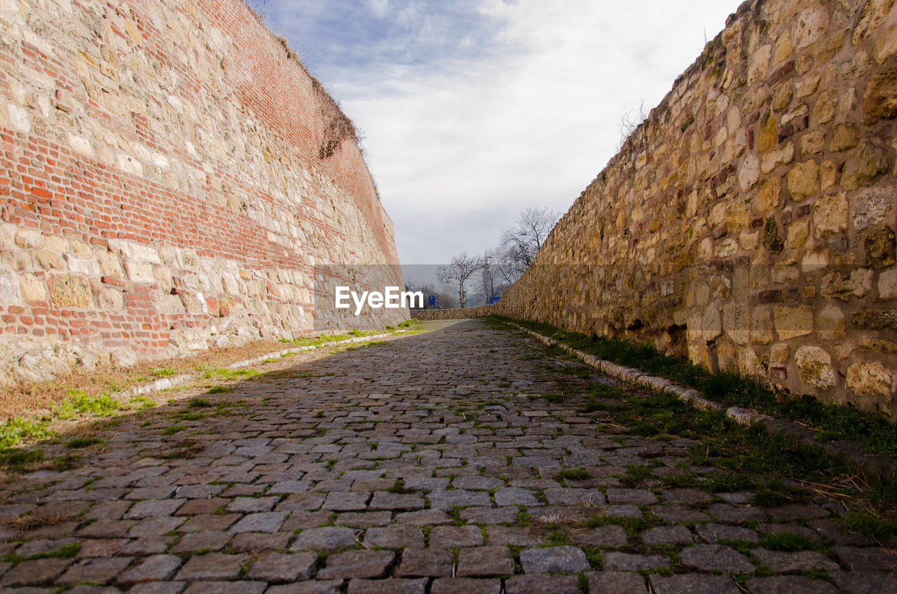 Footpath amidst wall against sky