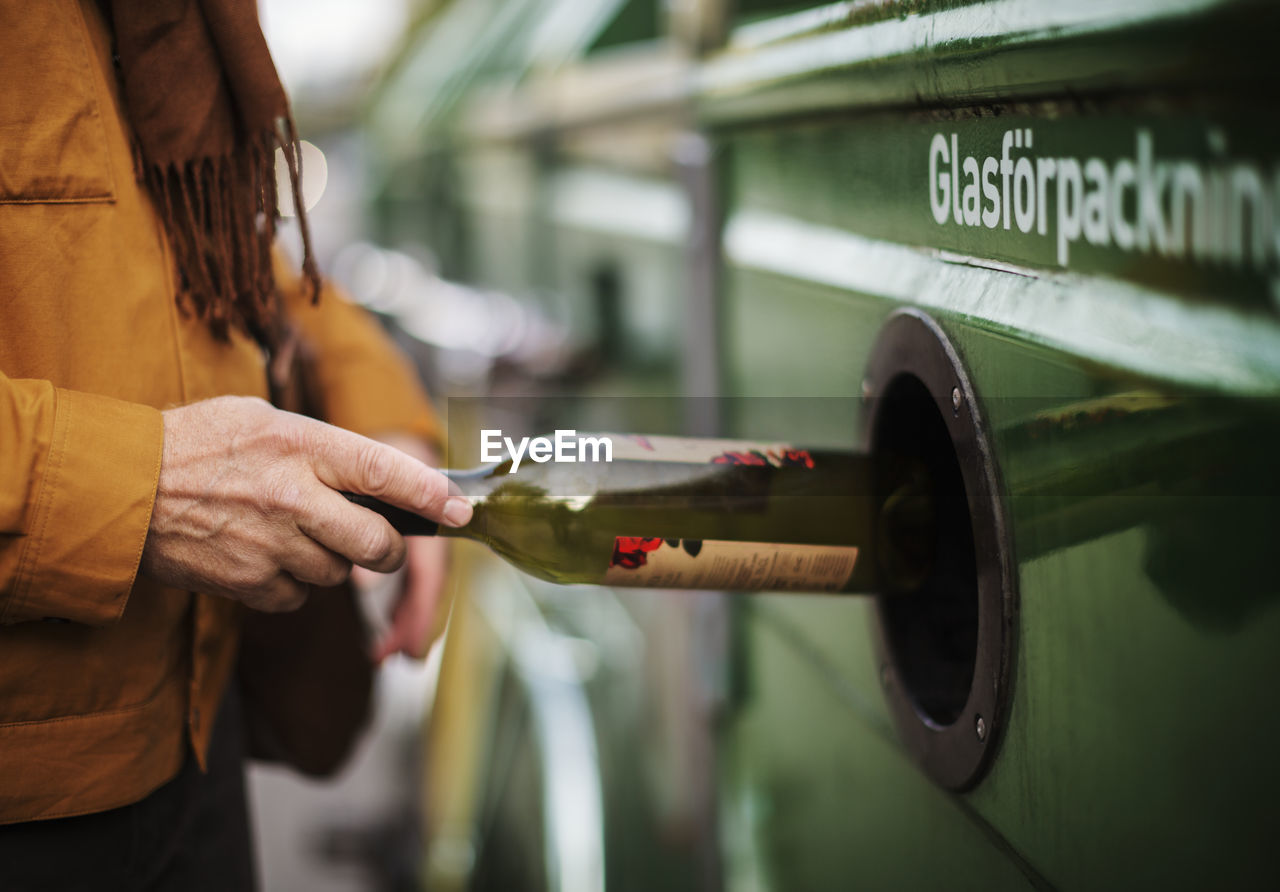 Hand putting bottle into recycling bin