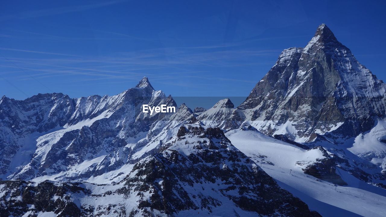 Scenic view of snowcapped mountains against blue sky