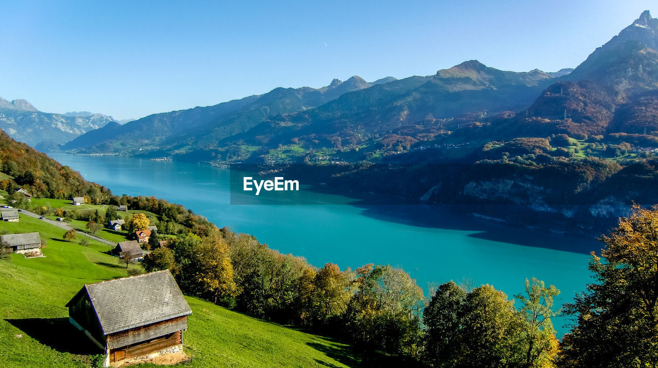 Scenic view of houses and mountains against clear blue sky