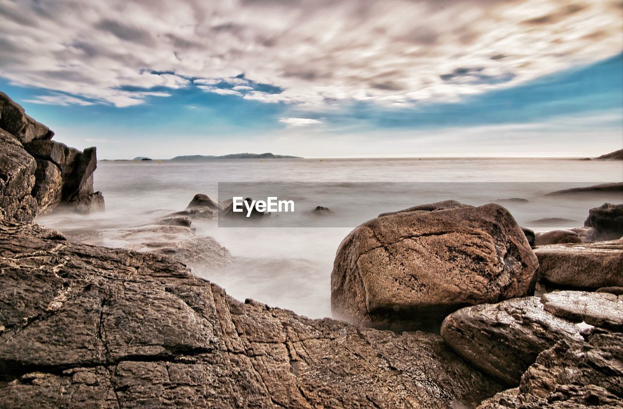 Rocks on sea shore against sky