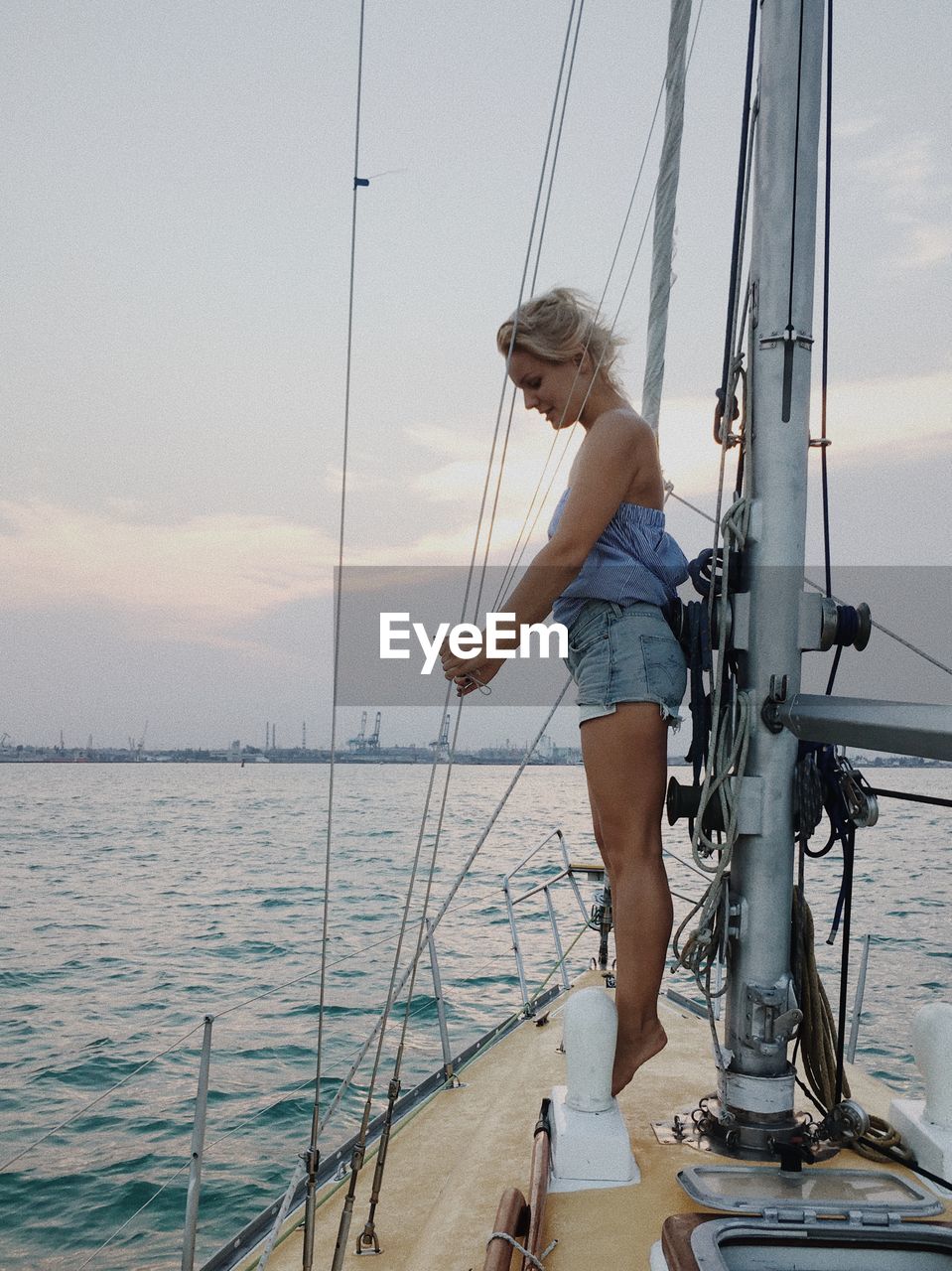 Young woman in boat sailing on sea against sky