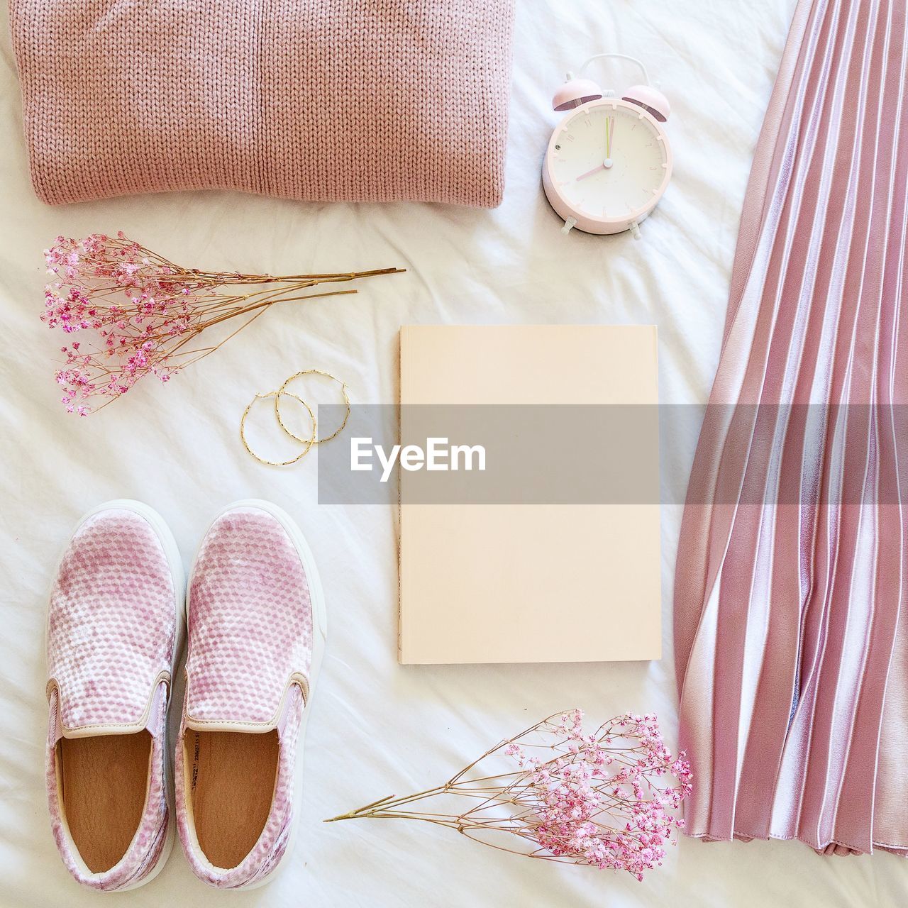 Directly above shot of shoes and book and flowers on bed