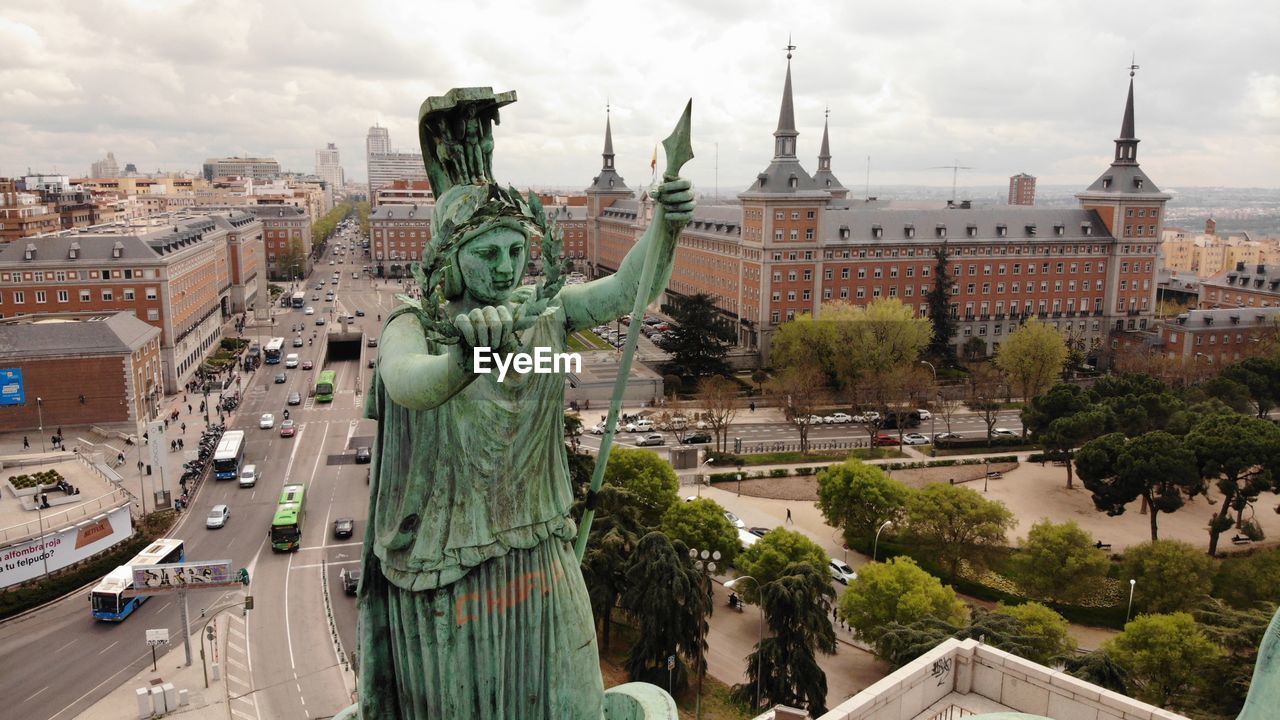 Statue in city against sky