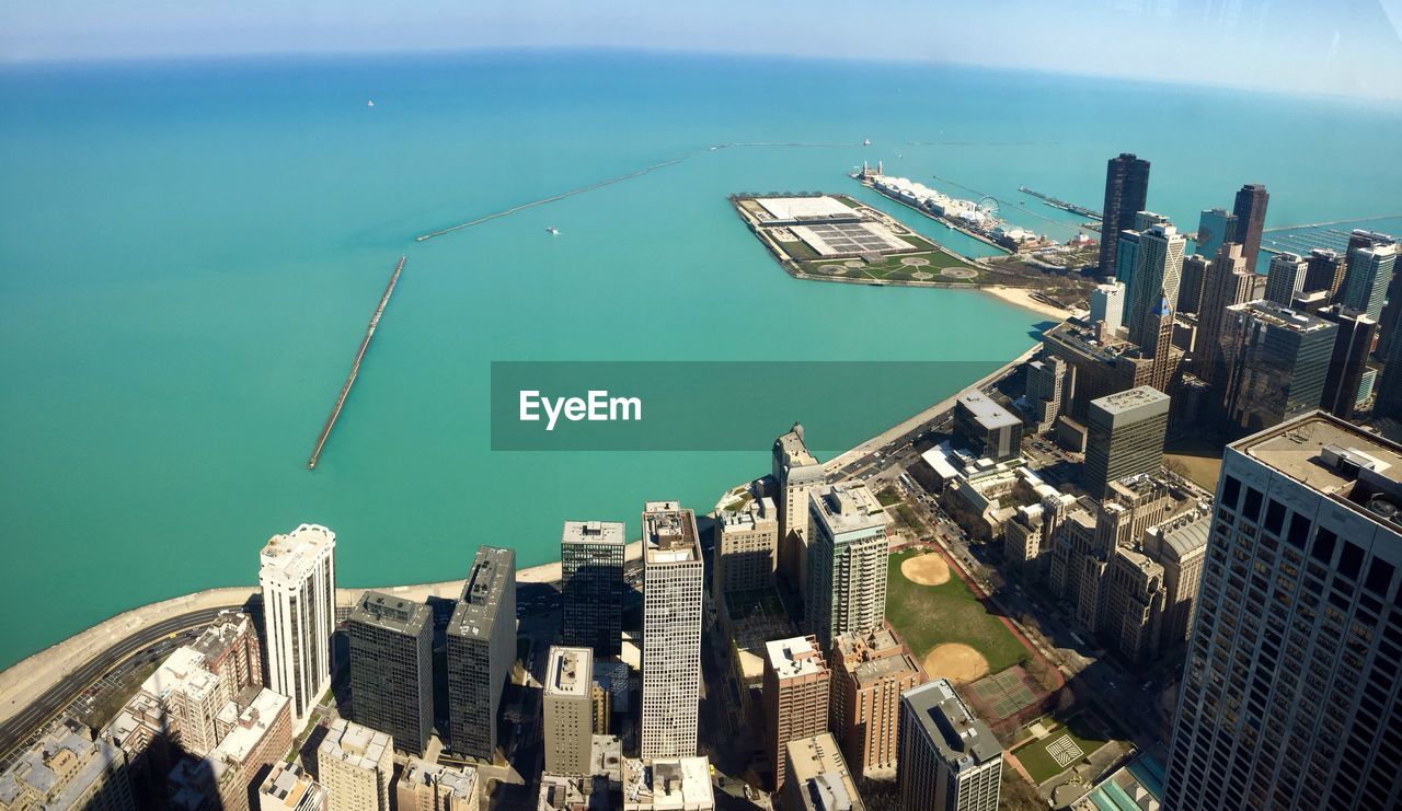 Aerial view of city by sea against sky