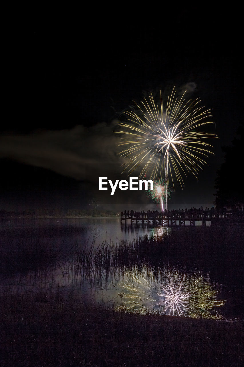 FIREWORK DISPLAY OVER LAKE AGAINST SKY