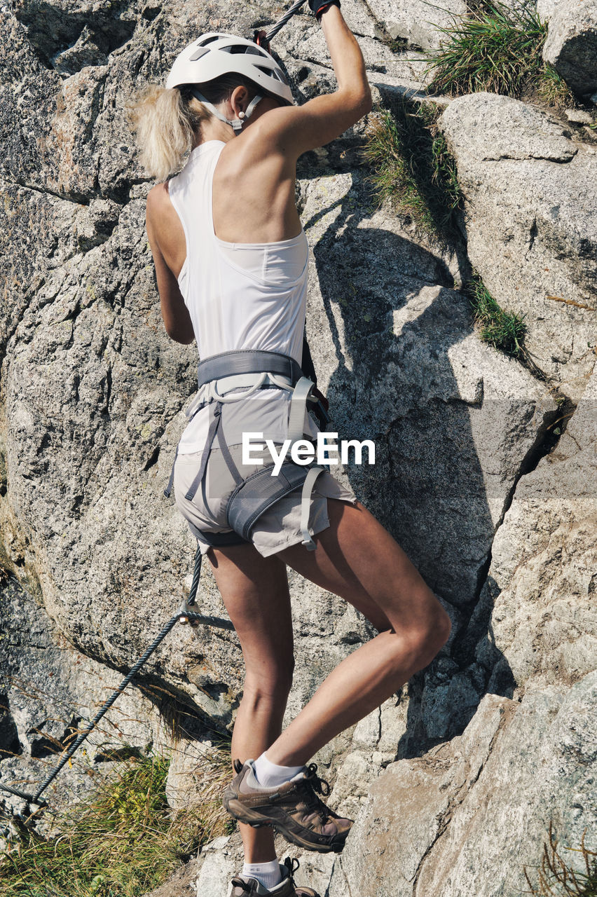 Rear view of woman climbing rock