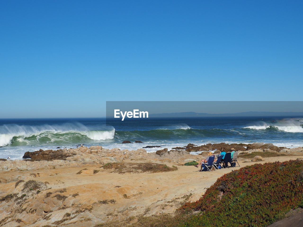 People on beach against clear sky