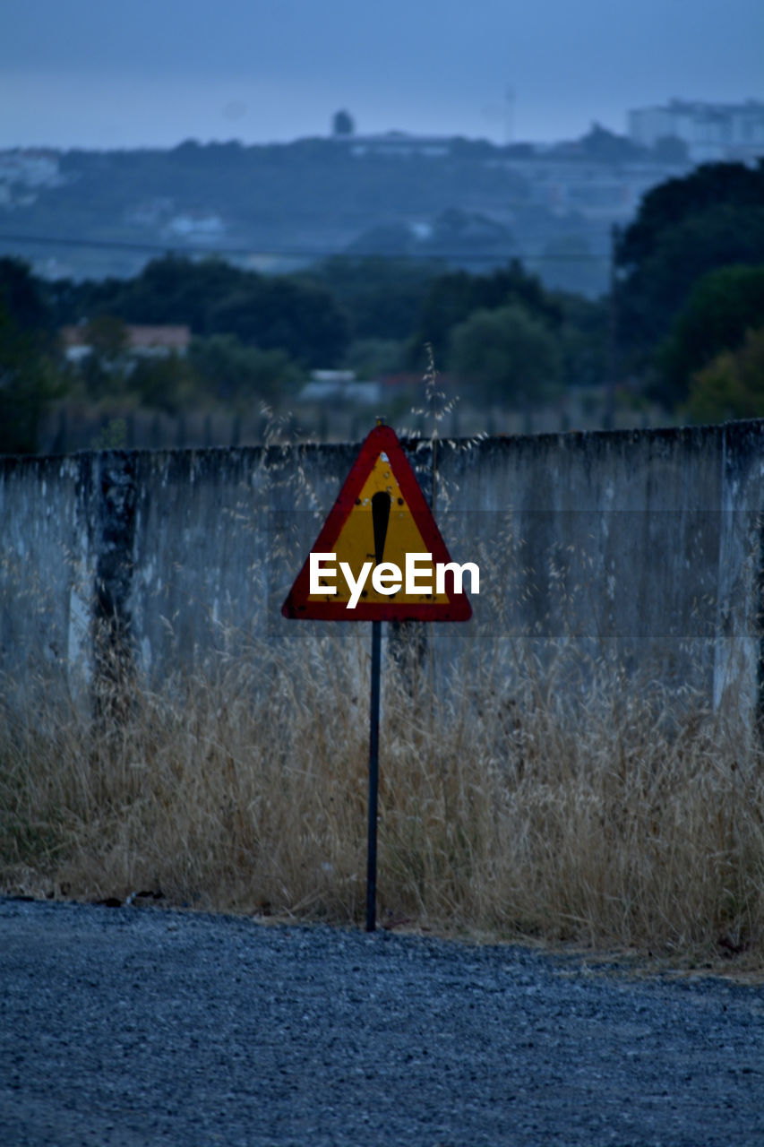 sign, communication, warning sign, blue, road sign, no people, nature, road, triangle shape, reflection, evening, sky, winter, water, mountain, shape, guidance, outdoors, day, sea, environment, landscape, plant, traffic sign, land, representation, cloud, scenics - nature