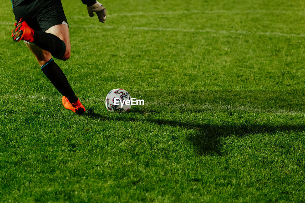 low section of man playing soccer on grassy field