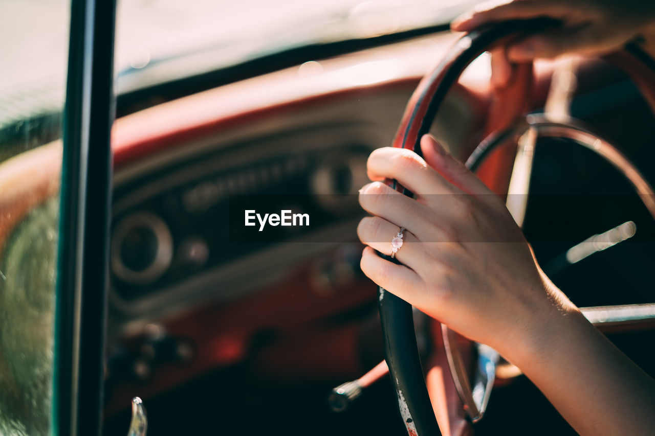 Cropped hand of woman holding steering wheel in car