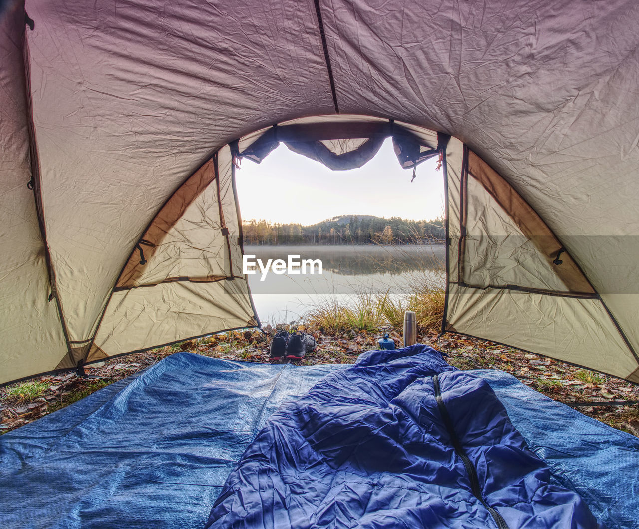 Tent on romantic place at lake shore. colorful fall forest. hilly horizon with last sun beams.