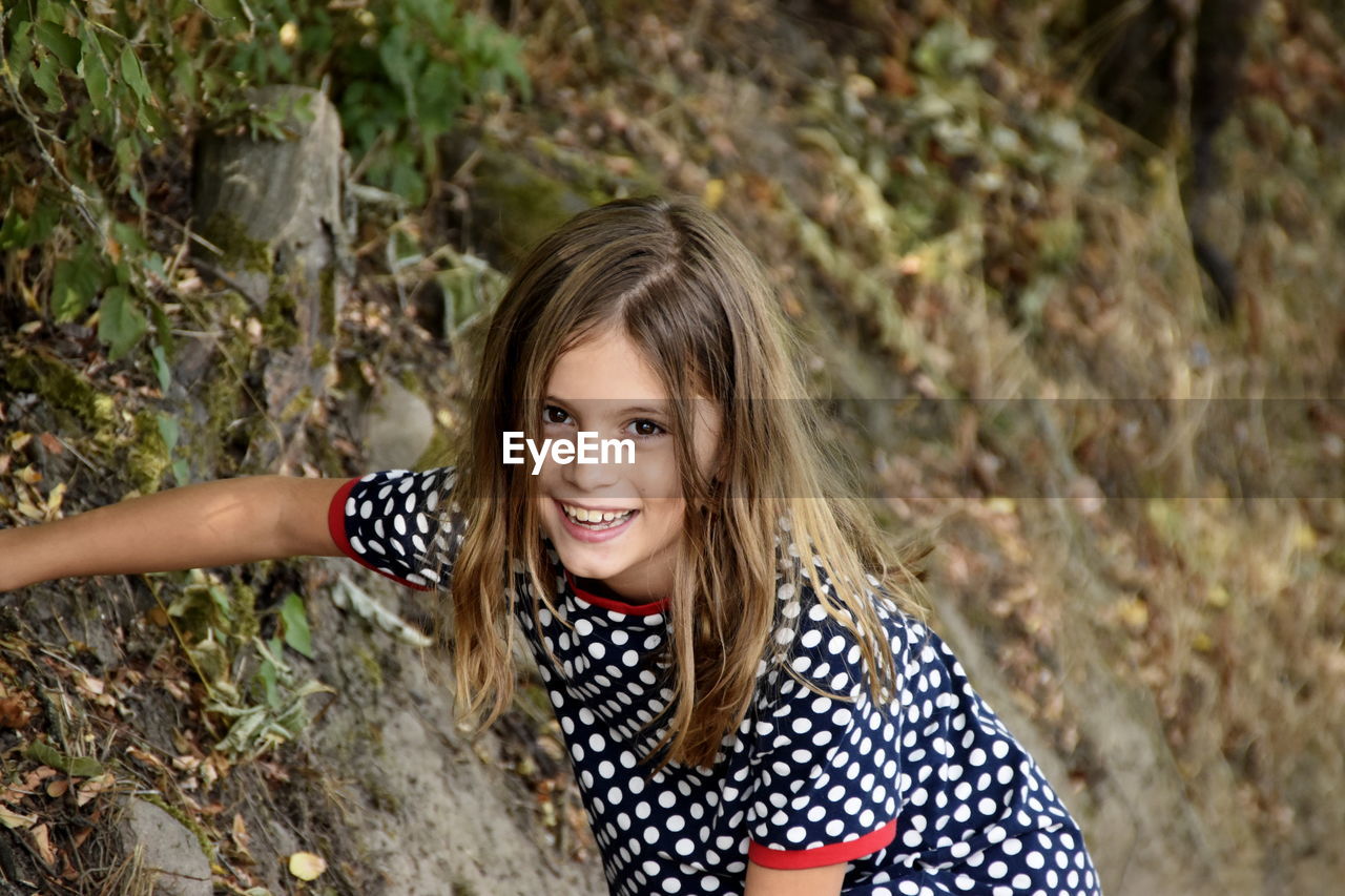 High angle portrait of cute cheerful girl in forest