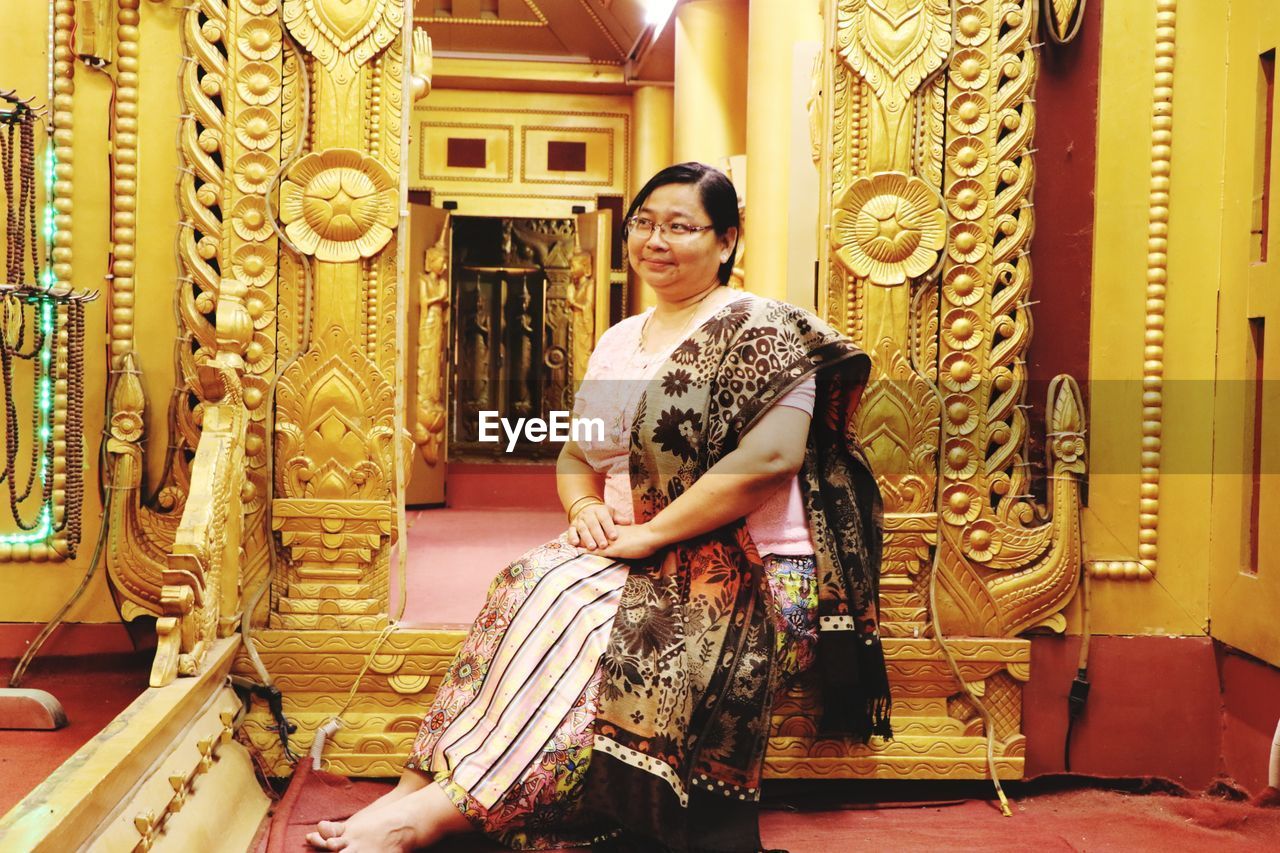 Smiling woman in traditional clothing sitting in temple