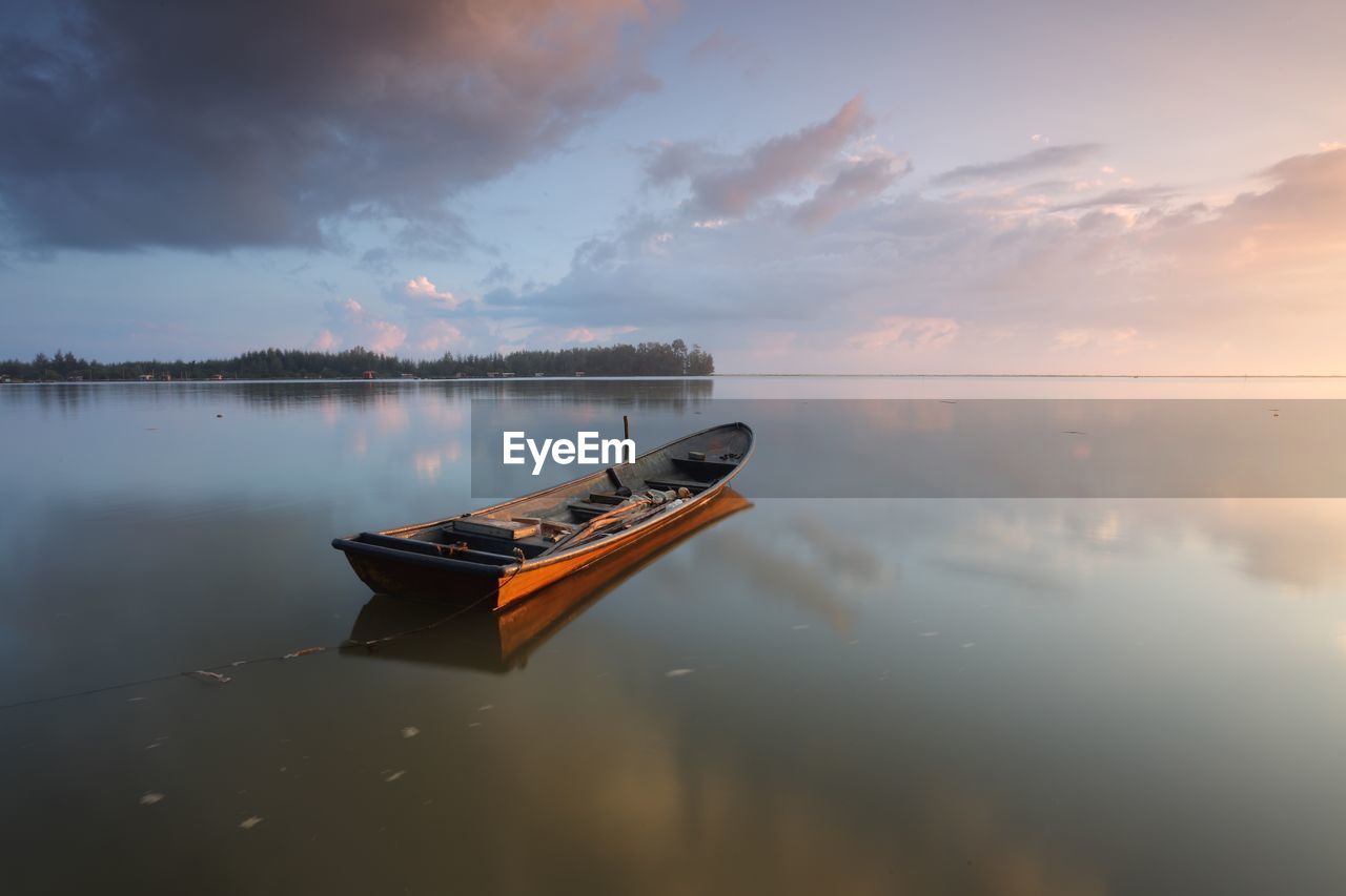 Fishing boat moored on lake during sunset