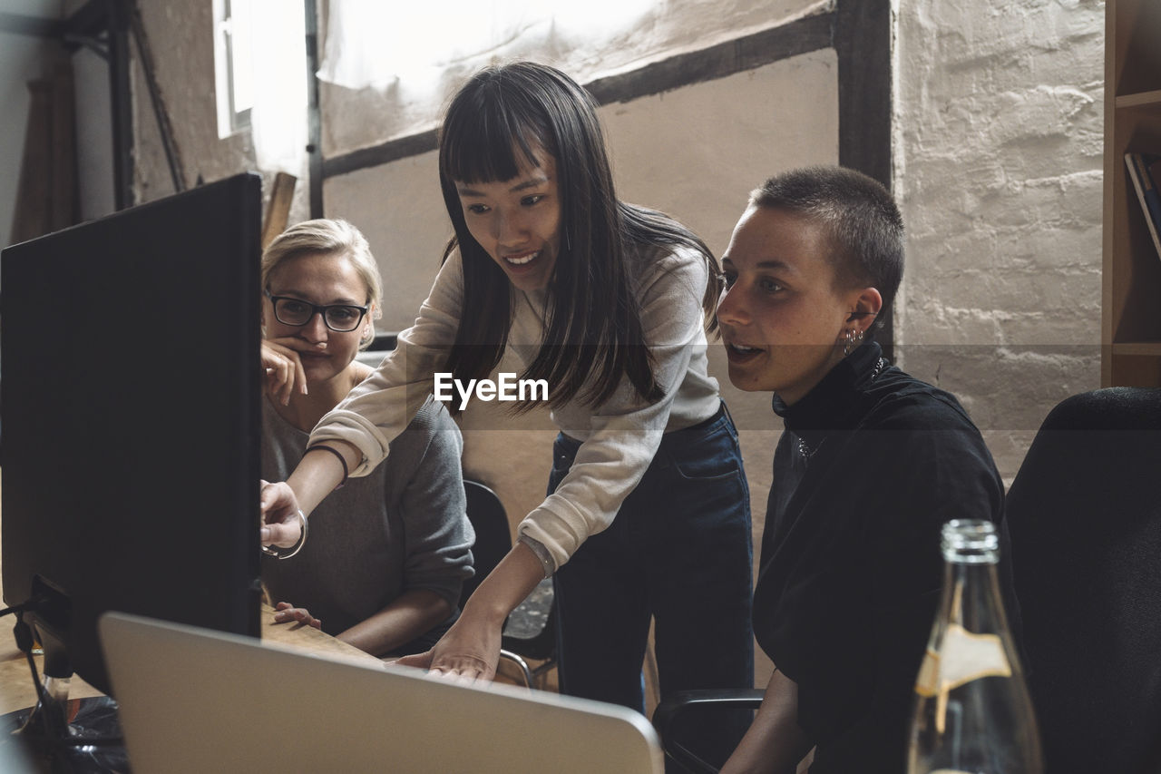 Smiling entrepreneur discussing with coworkers at workplace