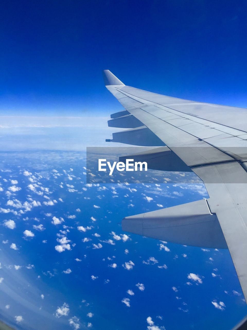 CROPPED IMAGE OF AIRPLANE WING OVER CLOUDS