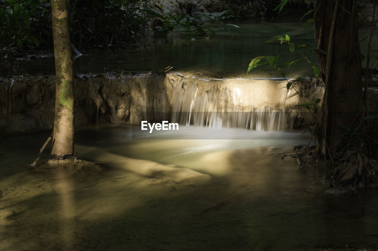 waterfall, water, nature, tree, plant, forest, beauty in nature, scenics - nature, reflection, long exposure, environment, darkness, motion, no people, jungle, land, water feature, river, flowing water, outdoors, sunlight, tranquility, landscape, non-urban scene, travel destinations, rainforest, blurred motion, idyllic