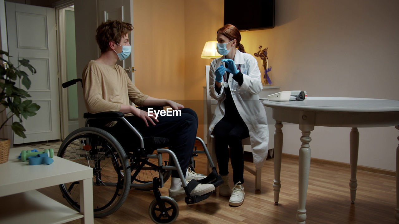 Young nurse checking temperature of patient at home