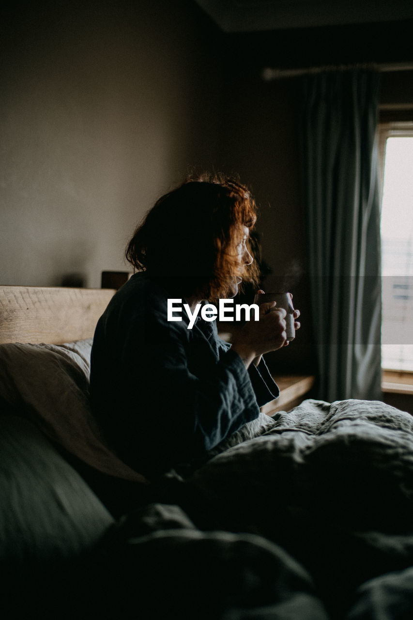 Side view of woman having coffee at home