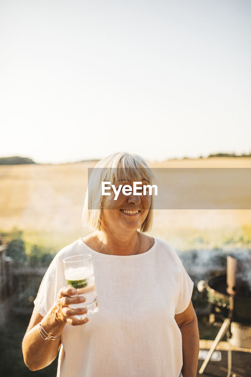 Smiling woman in garden holding drink