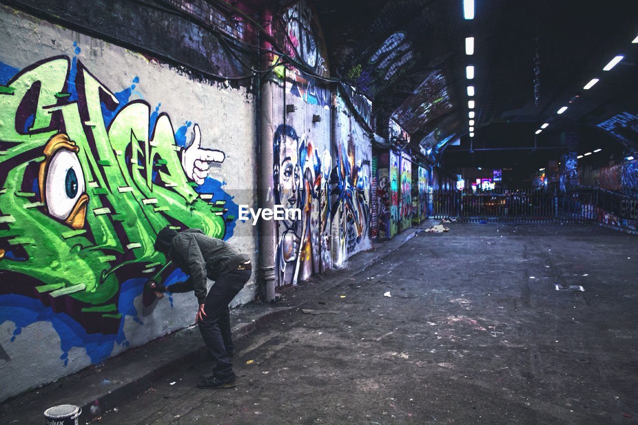 Man drawing graffiti on wall