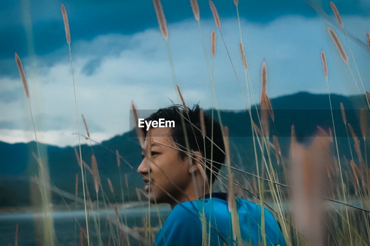 Portrait of young woman looking away against sky