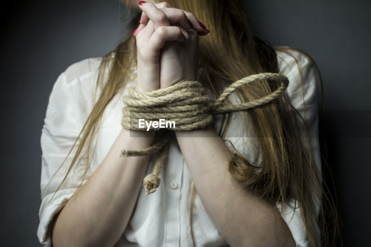 CLOSE-UP OF YOUNG WOMAN TIED UP WITH HANDS