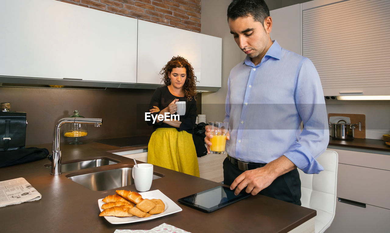 Couple having breakfast while standing in kitchen