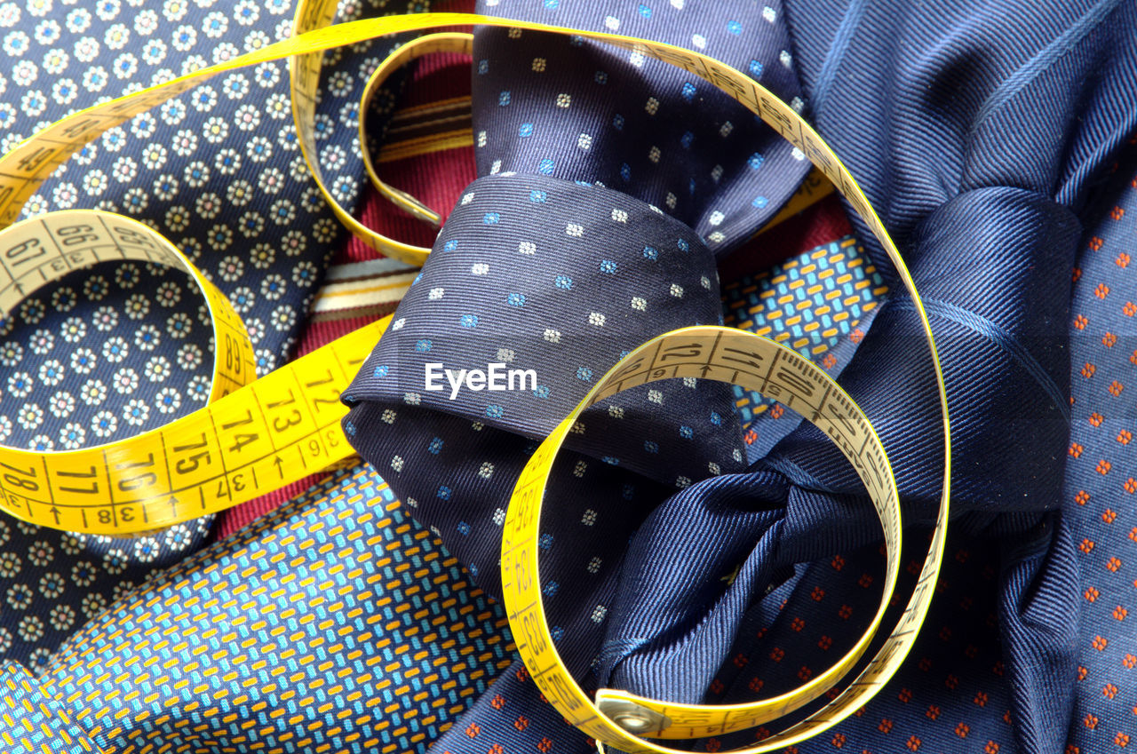 High angle view of necktie and tape measure on textile