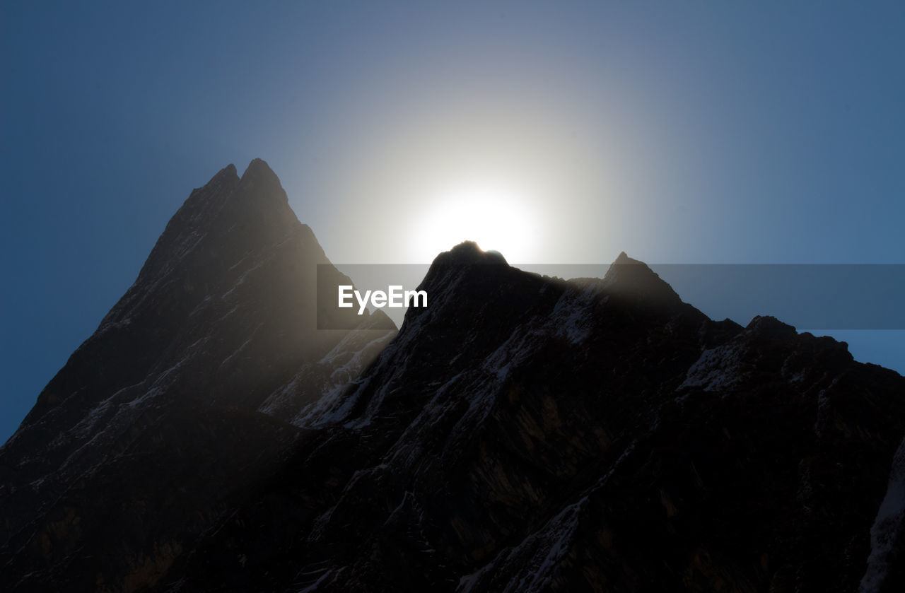 Low angle view of rocky mountains against clear sky