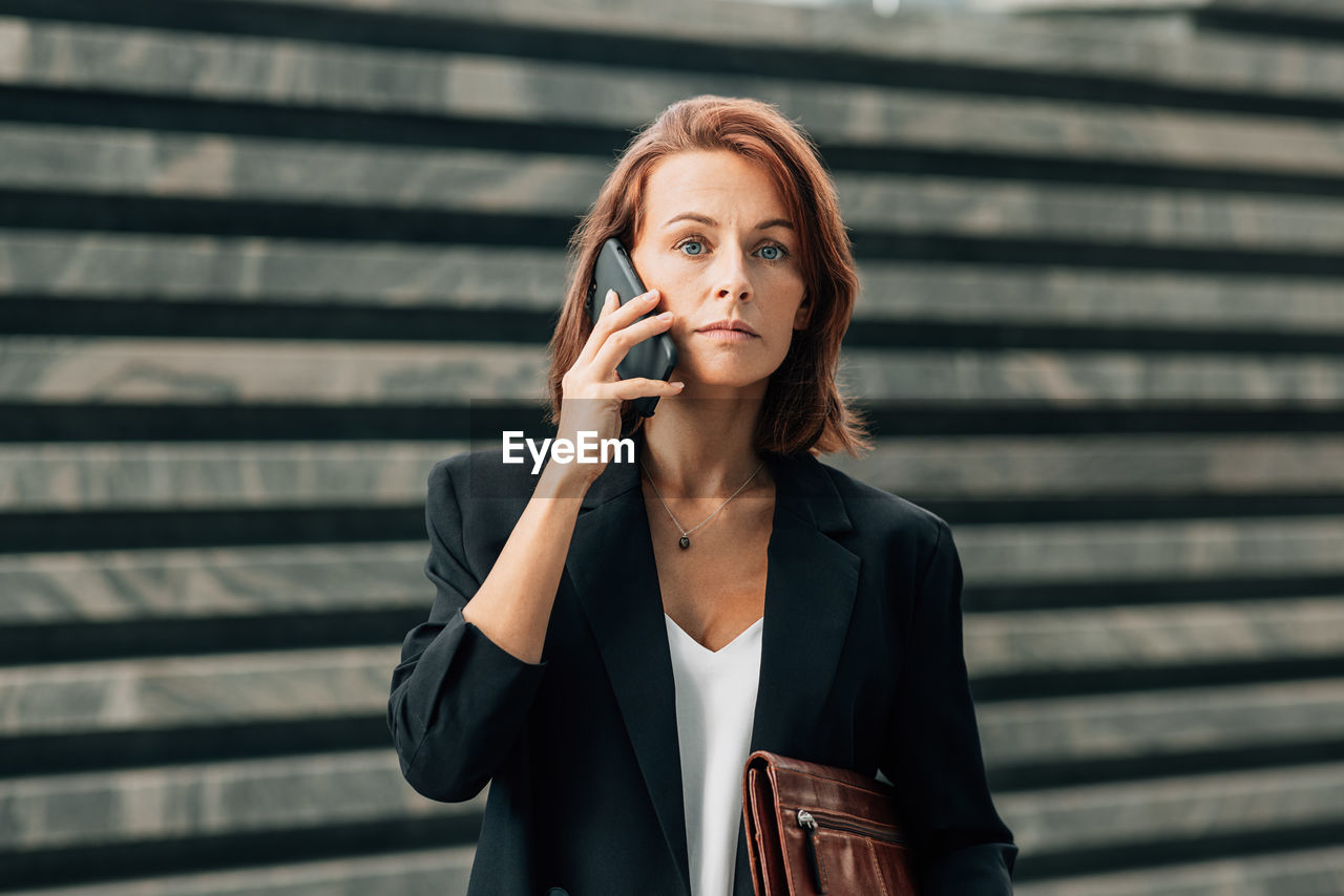 portrait of young businesswoman standing against wall