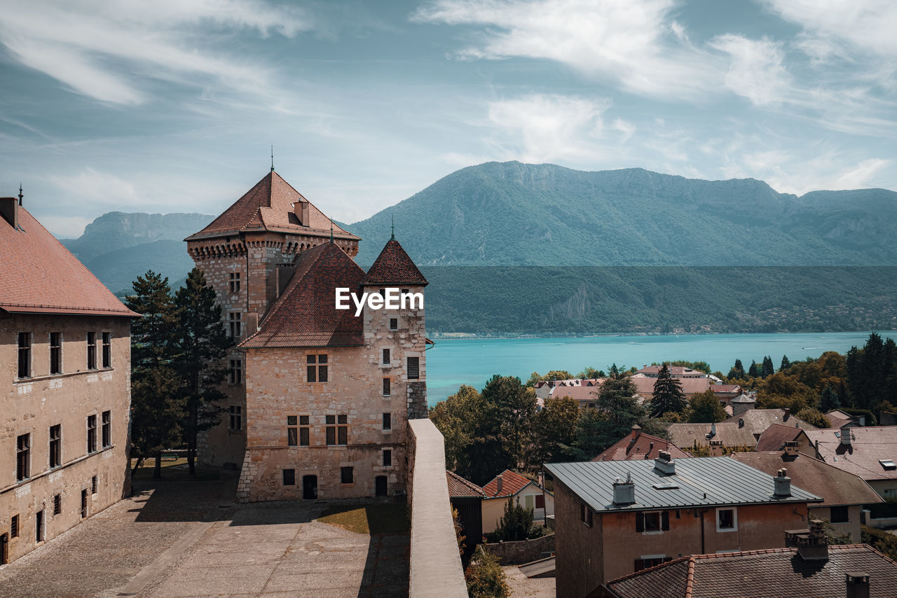 Castle in town in front of lake against mountain and sky