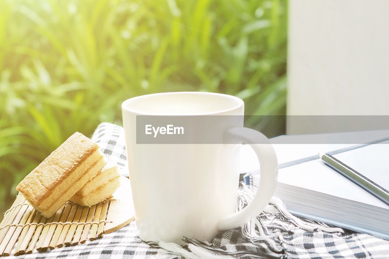 CLOSE-UP OF COFFEE CUP ON TABLE AGAINST WALL