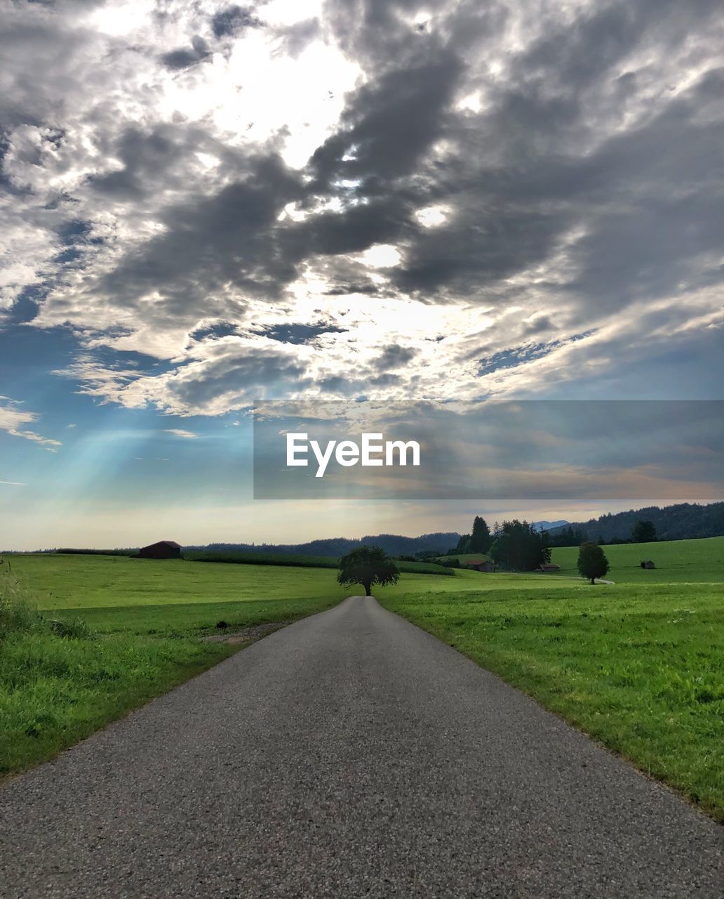 ROAD BY FIELD AGAINST SKY