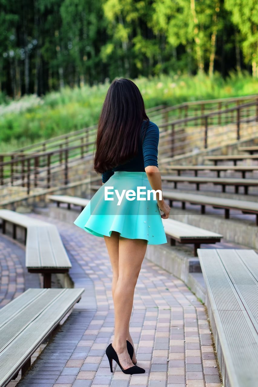 Rear view full length of young woman standing by bleachers at amphitheater