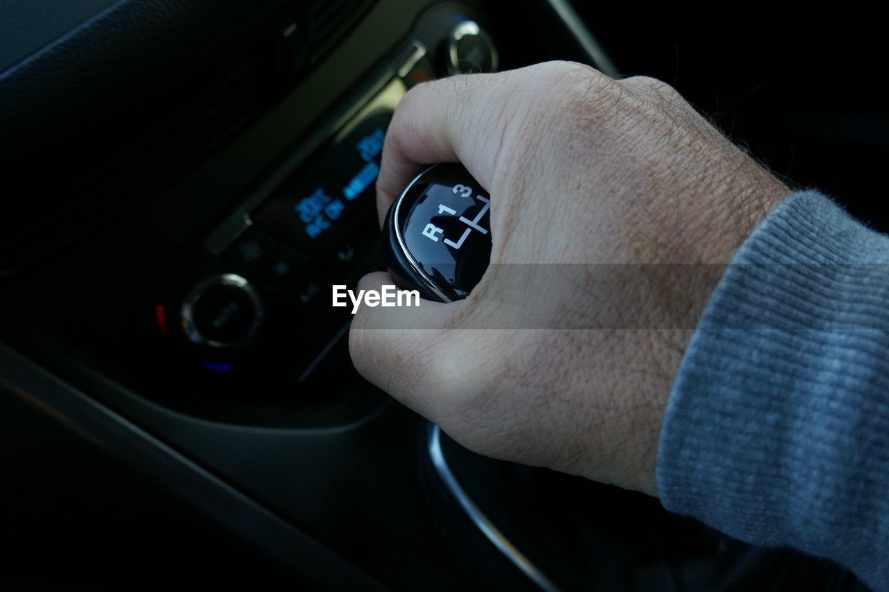 Cropped image of hand shifting gear in car