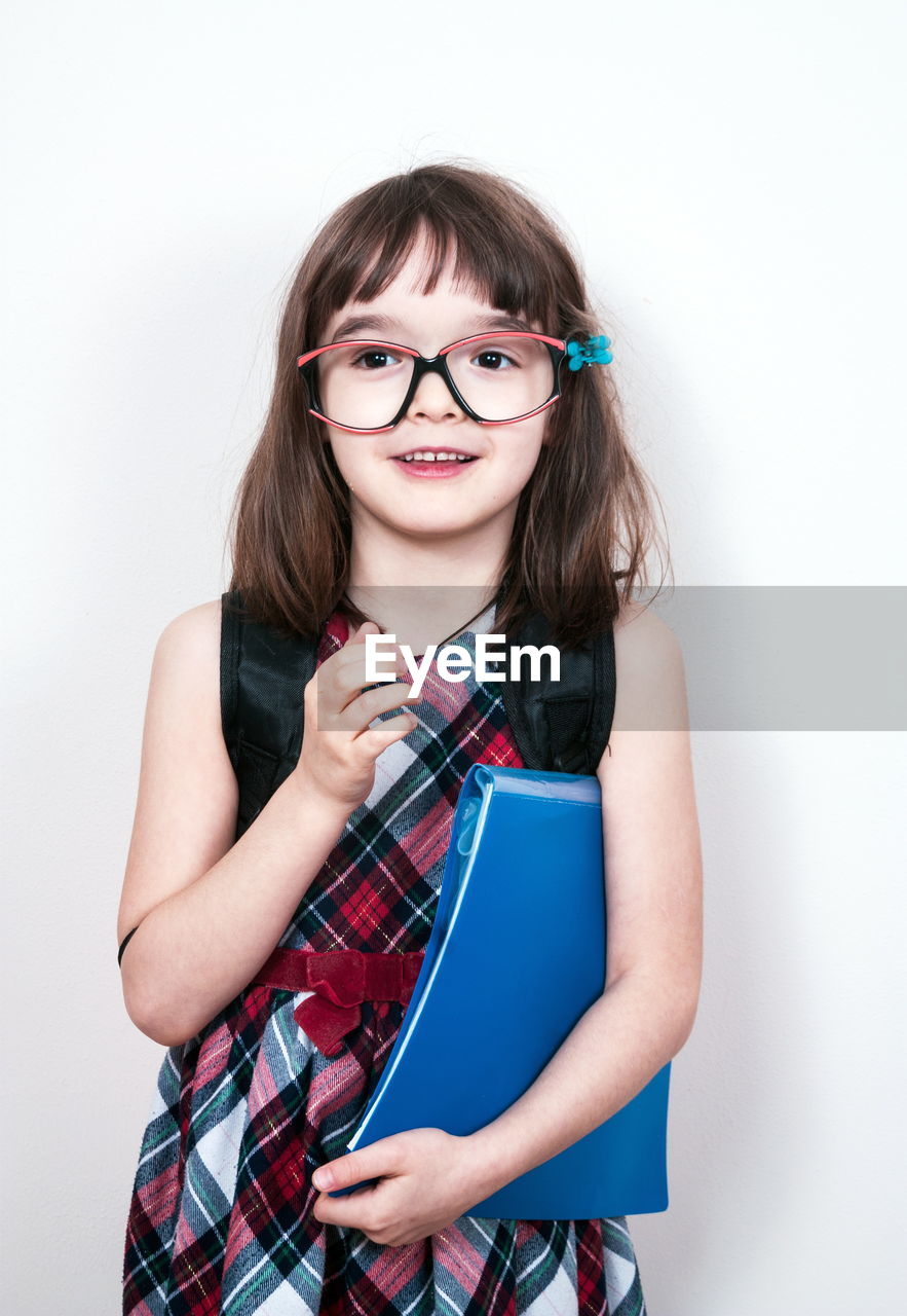 portrait, one person, looking at camera, glasses, child, women, eyeglasses, studio shot, white background, smiling, indoors, childhood, happiness, hairstyle, photo shoot, emotion, long hair, cute, female, student, clothing, waist up, front view, teenager, brown hair, fashion, education, adult, standing, cut out, cheerful, fun, vision care, young adult, casual clothing, holding, positive emotion