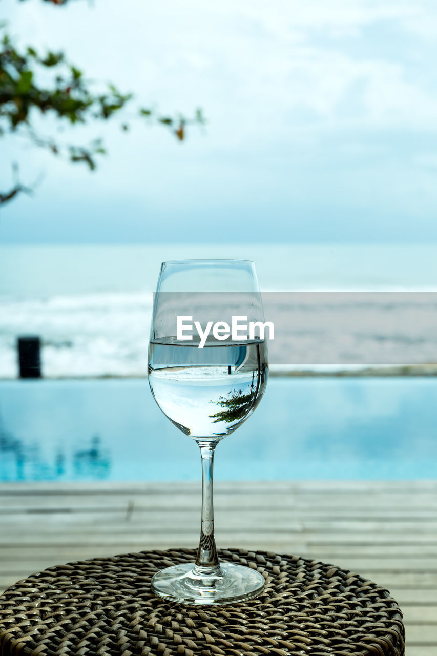 GLASS OF WATER ON TABLE BY SEA