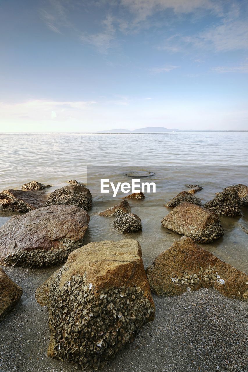 ROCKS ON BEACH AGAINST SKY