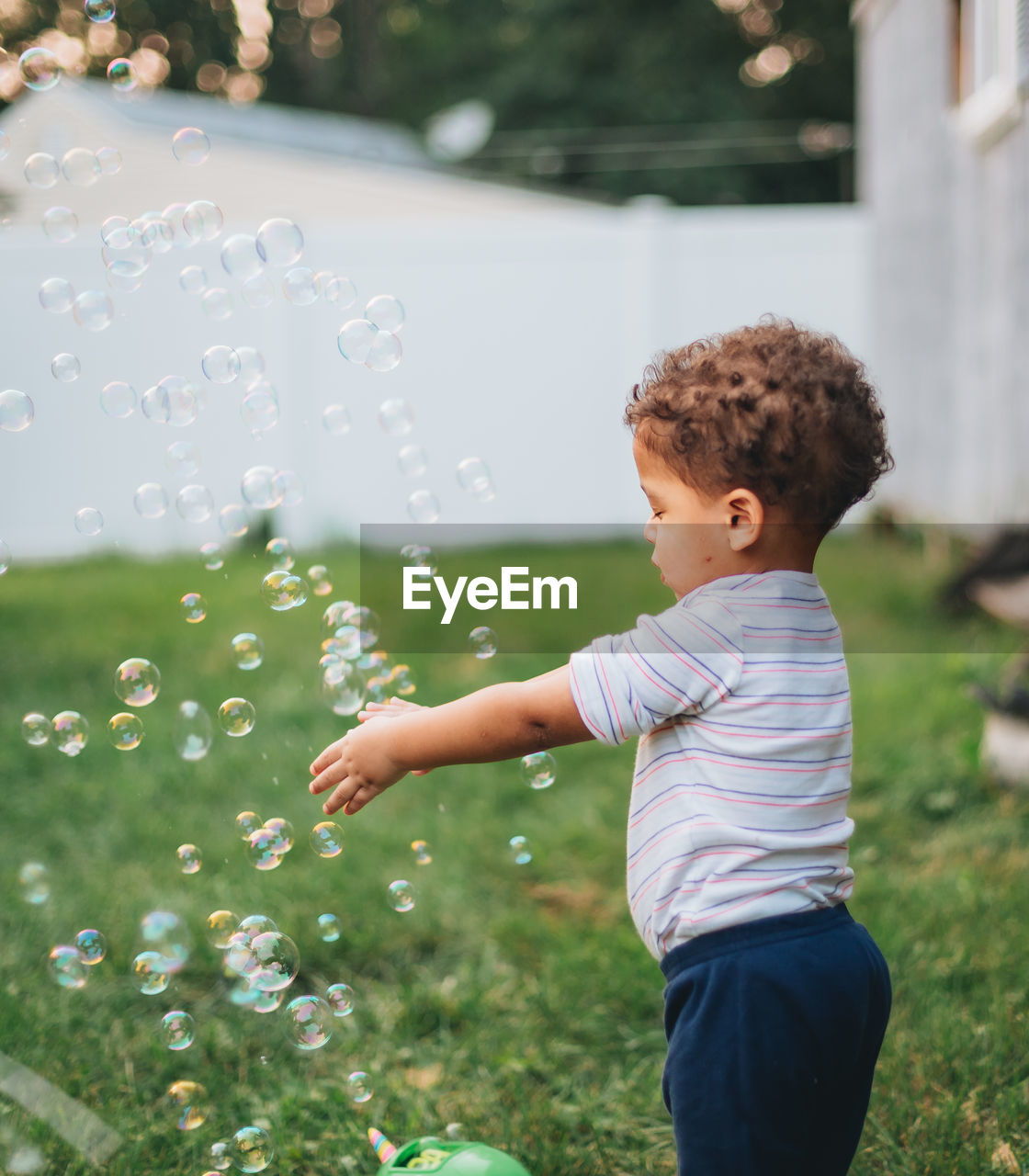 Diverse mixed race toddler boy at home in backyard playing with bubbles