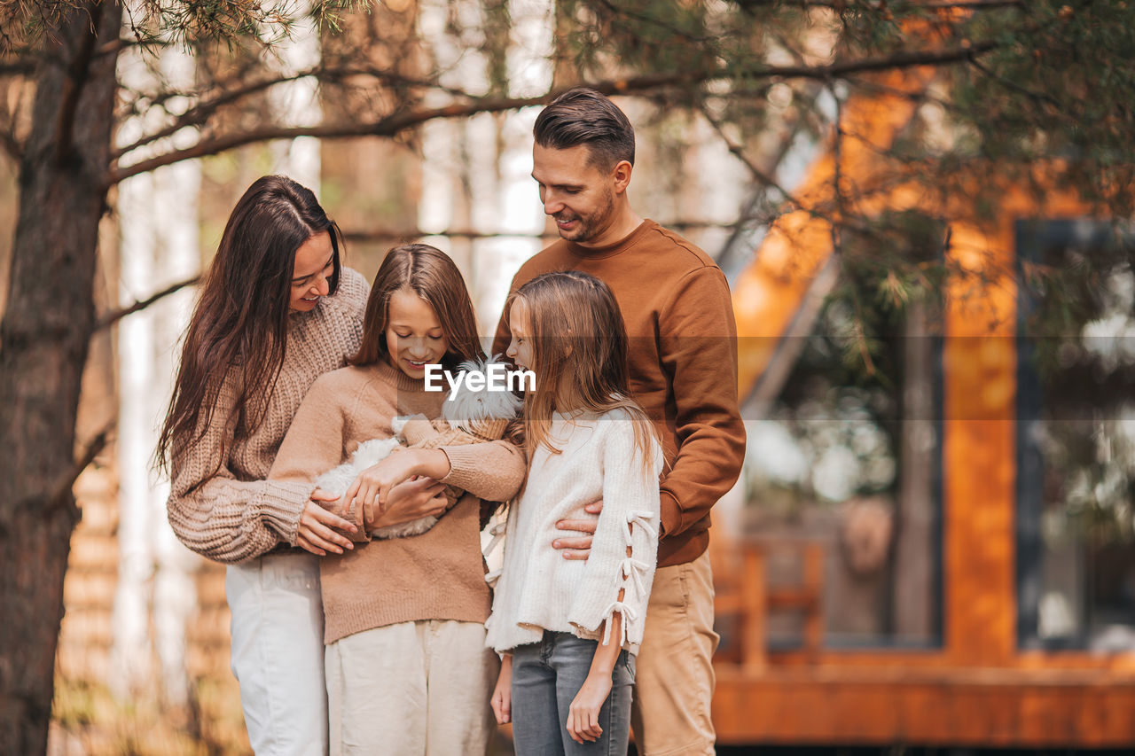 Cheerful family with dog standing outdoors