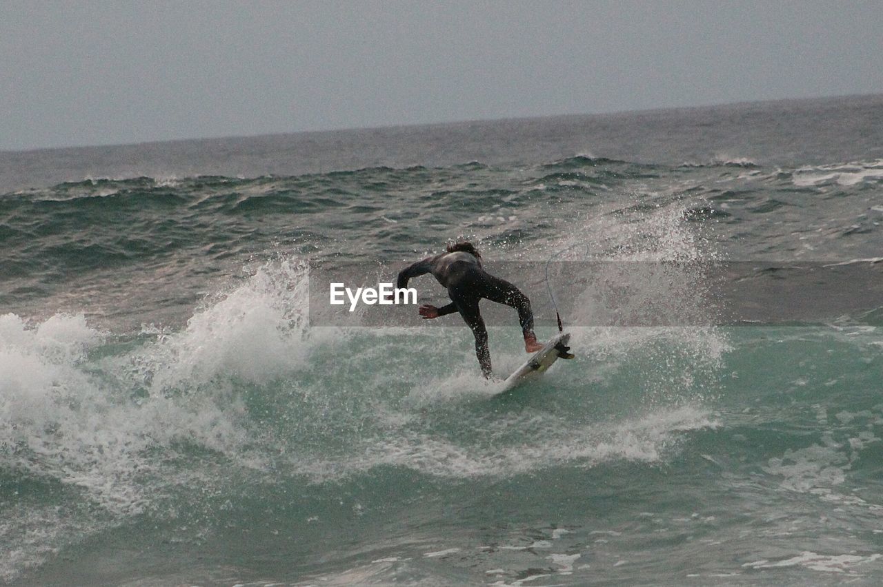 Man surfing in sea against sky