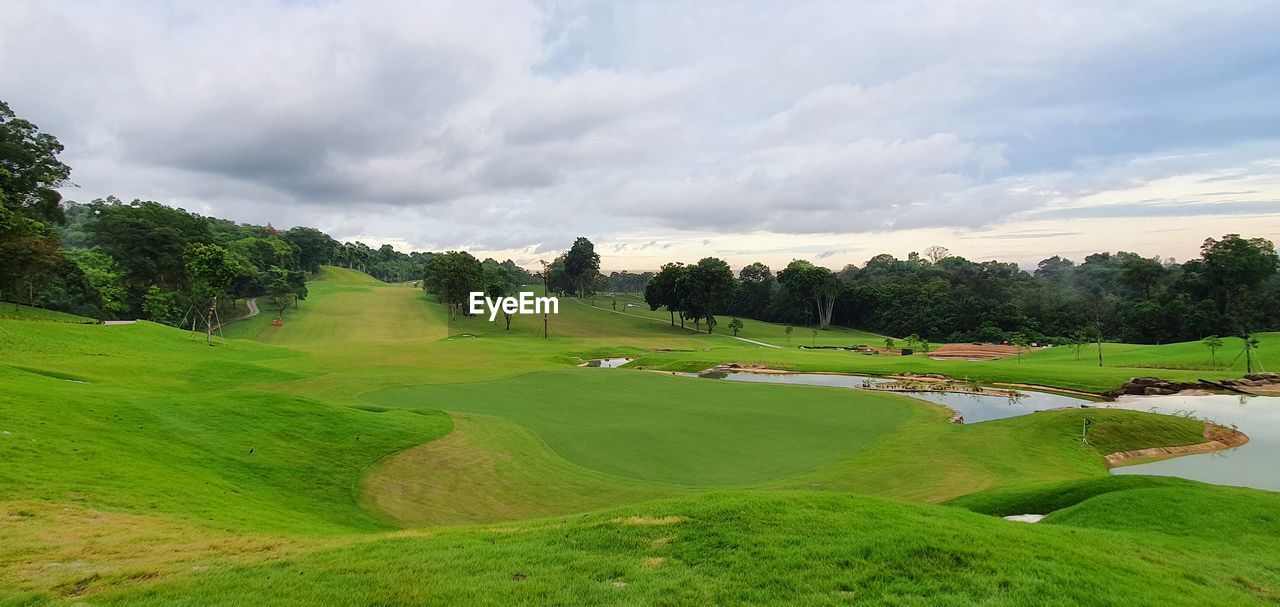 SCENIC VIEW OF GOLF COURSE AGAINST CLOUDY SKY