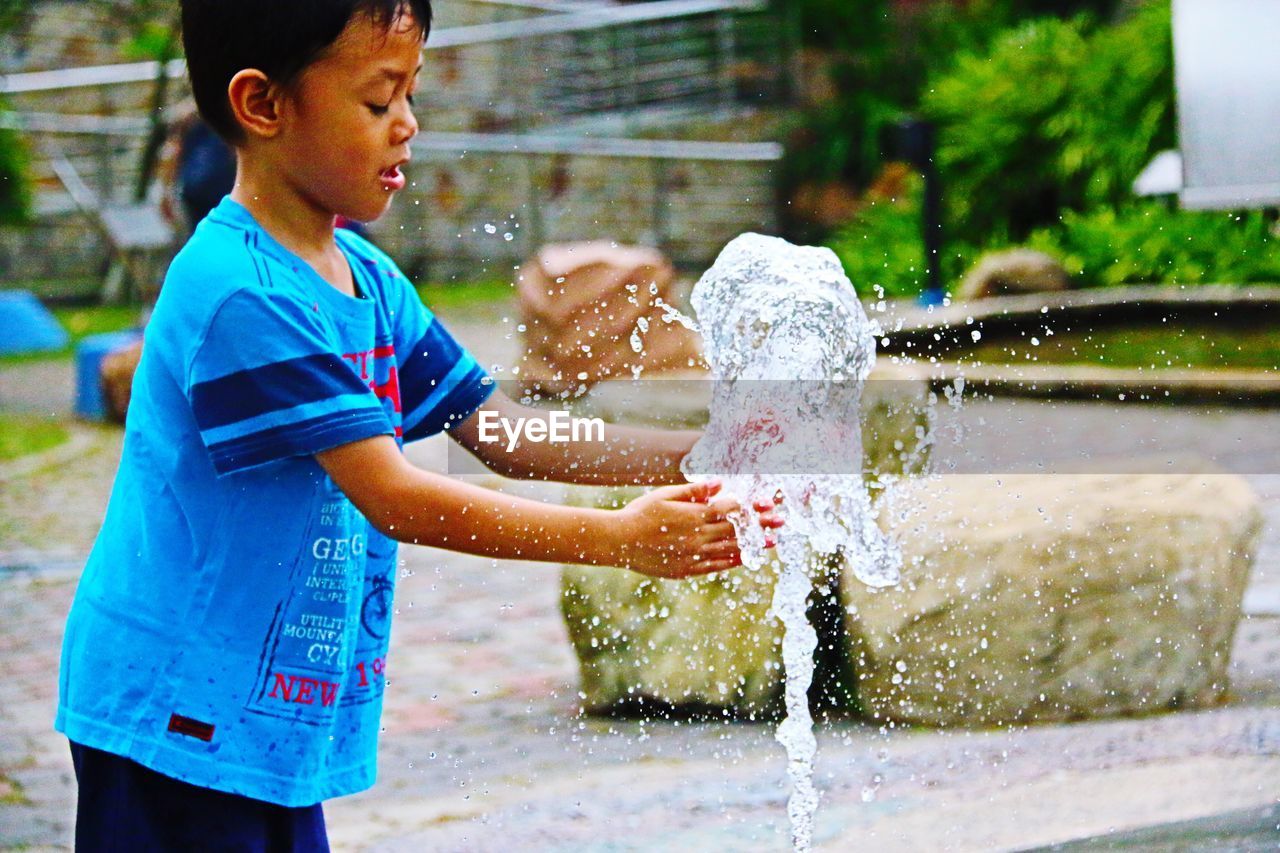 Boy playing fountain at water park