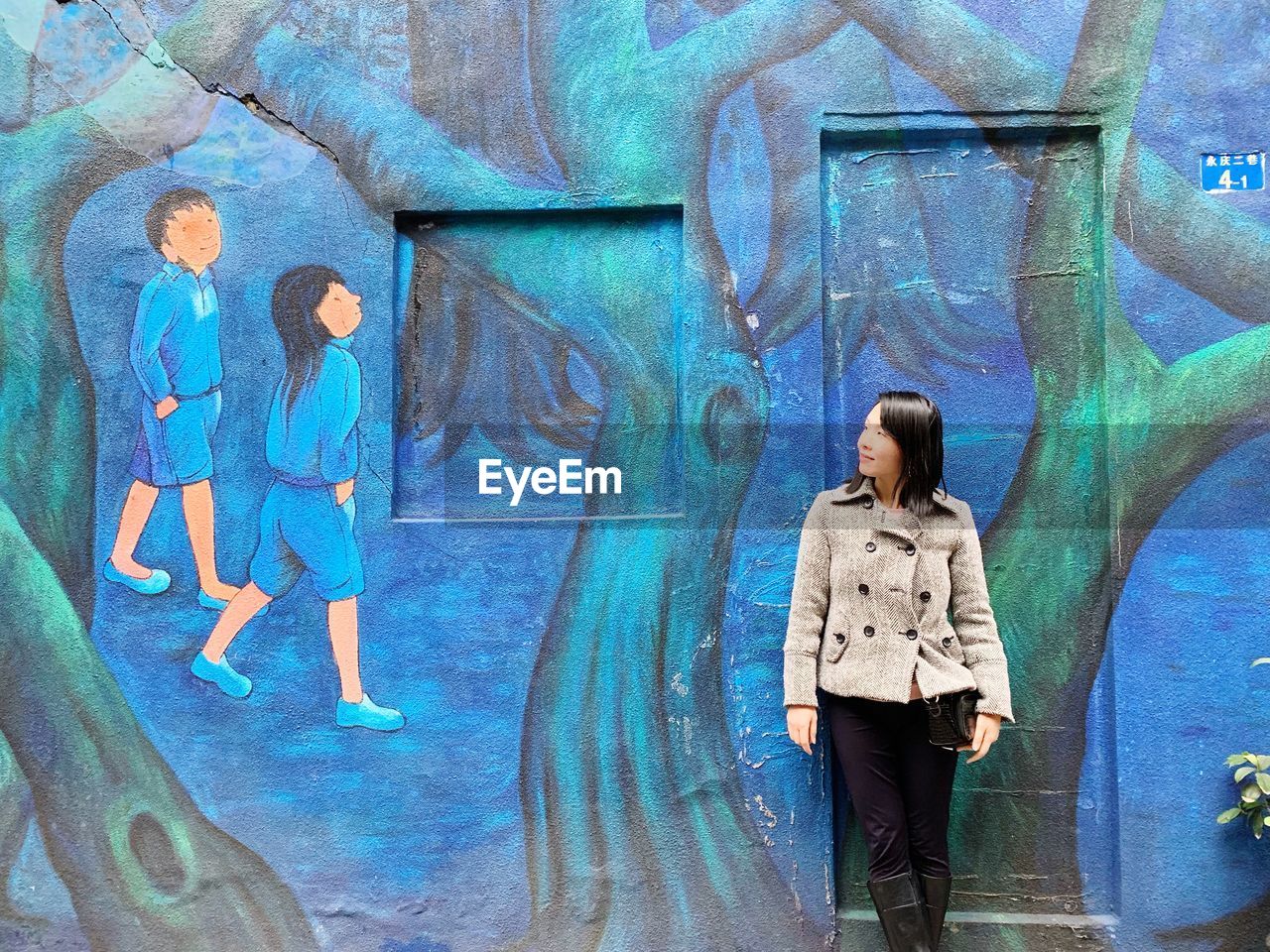 YOUNG WOMAN STANDING AGAINST GRAFFITI WALL