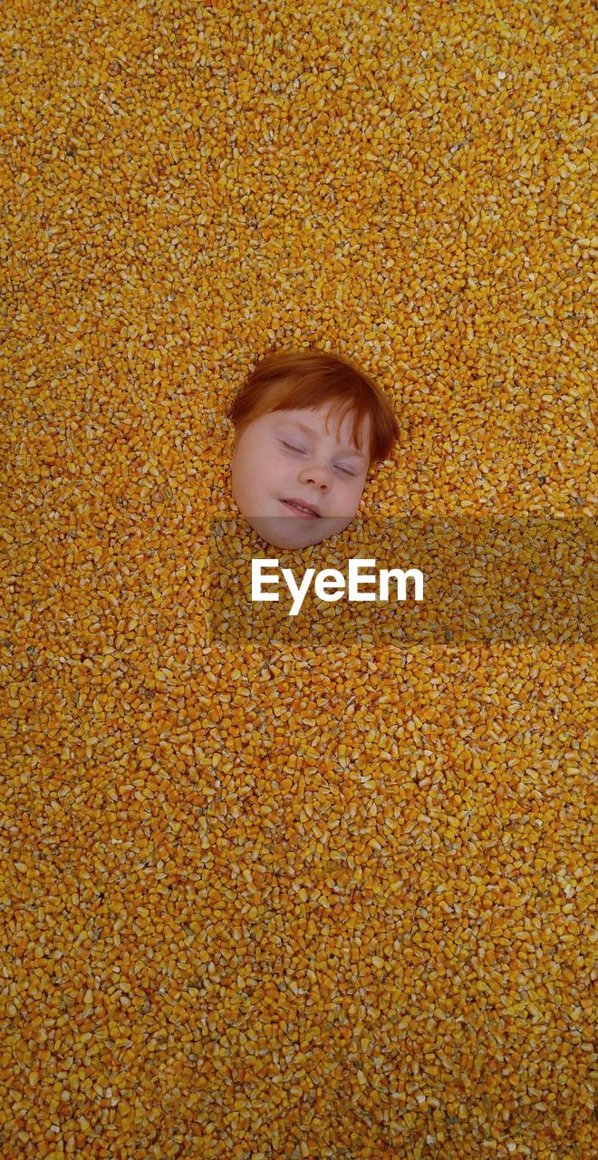 Directly above shot of girl covered with corn kernels