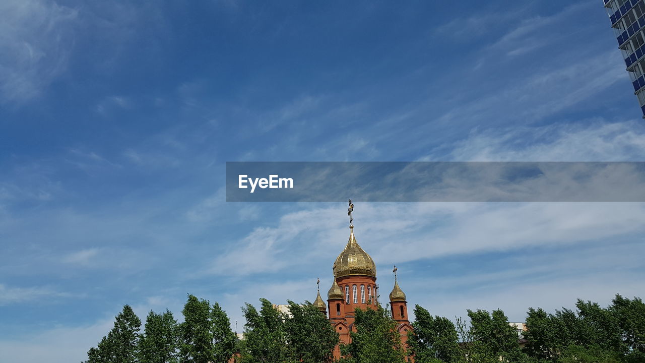 Low angle view of trees and building against sky