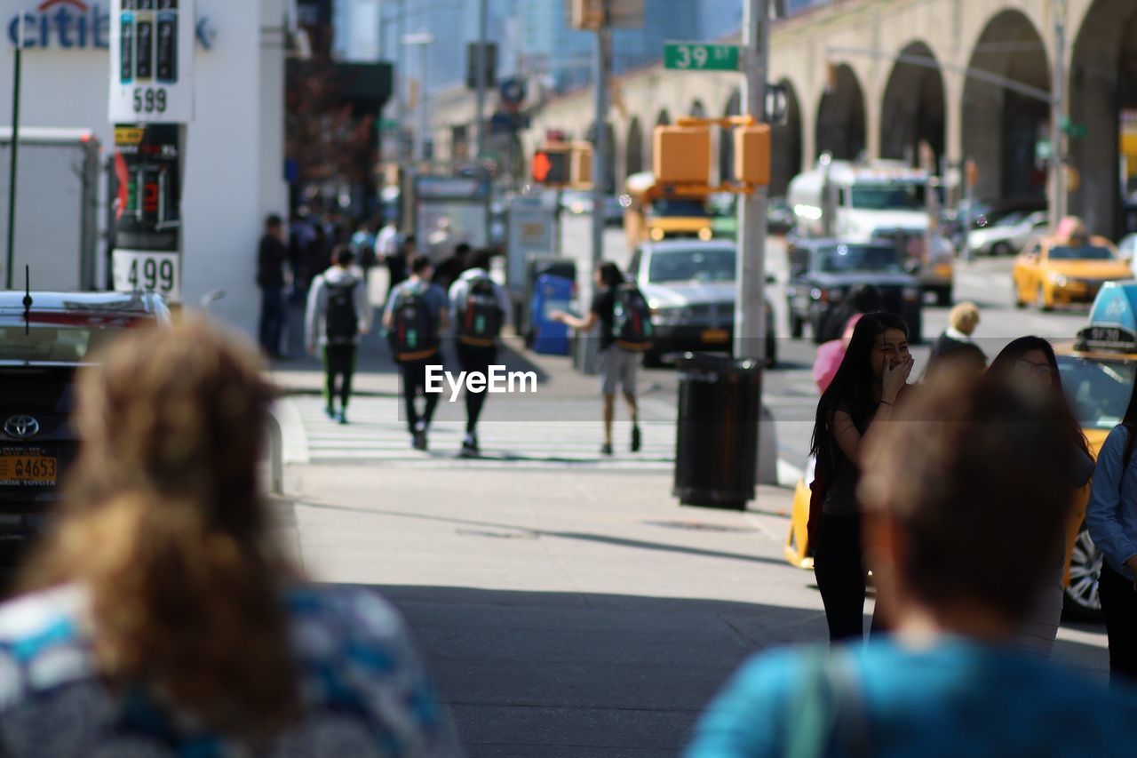 Tilt shift image of people on sidewalk in city